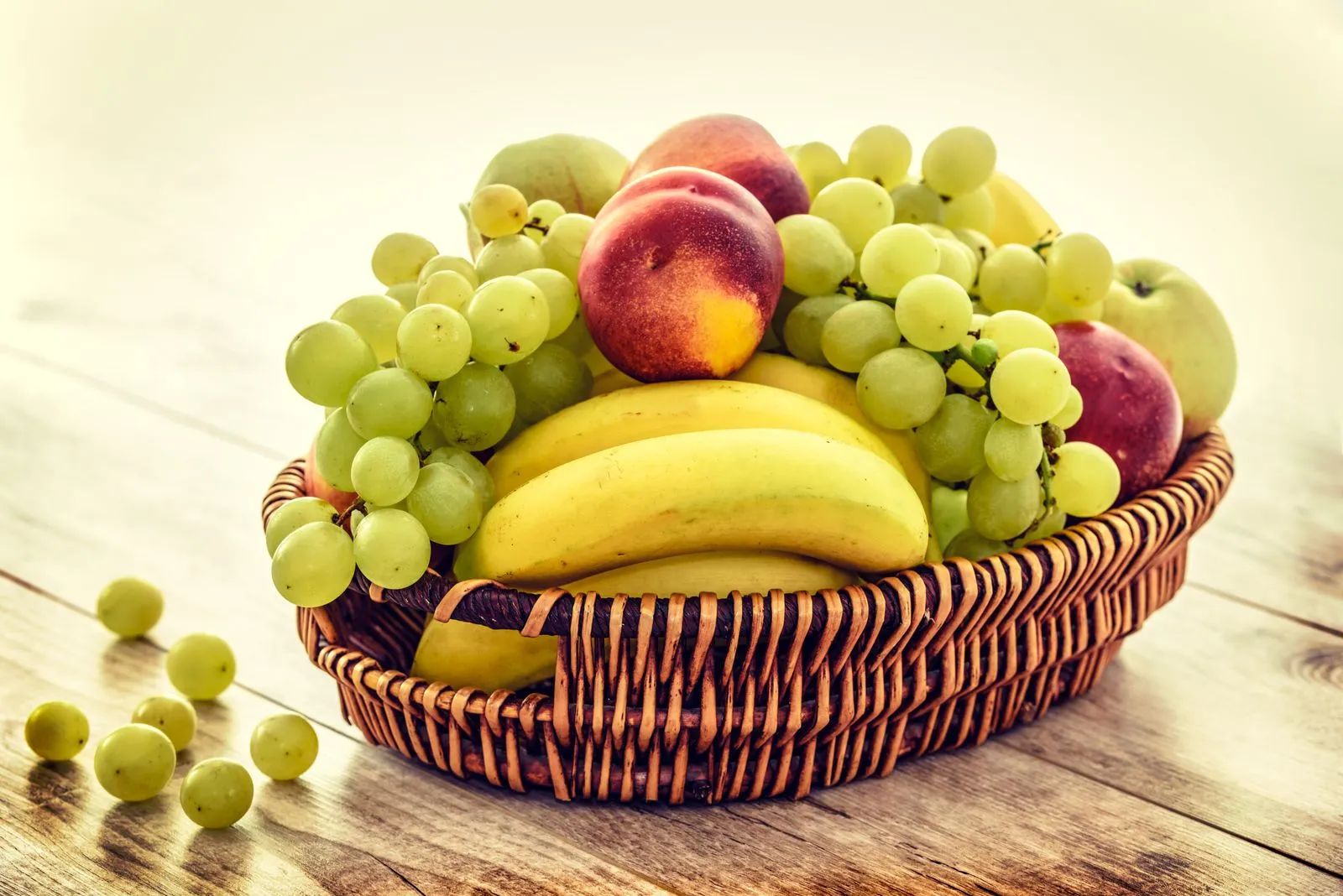 A basket of fresh fruit — grapes, bananas, apples and peaches